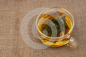 Cup of herbal tea in bags, on burlap, natural medium