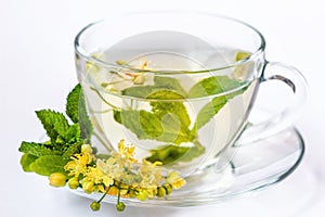 Cup of herbal tea with linden flowers, honey and mint in transparent cup isolated on white