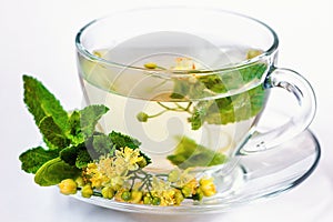 Cup of herbal tea with linden flowers, honey and mint in transparent cup isolated on white