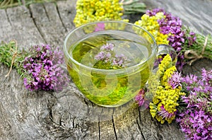 Cup of herbal tea and medicinal herbs on a wooden table. fresh thyme and immortelle. cold and flu remedy