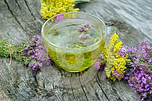 Cup of herbal tea and medicinal herbs on a wooden table. fresh thyme and immortelle. cold and flu remedy