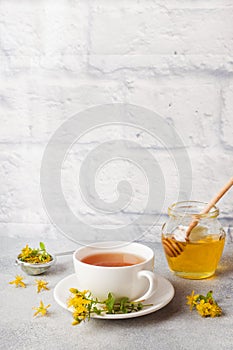 Cup with herbal tea from petals flowers Hypericum on grey background. Copy space