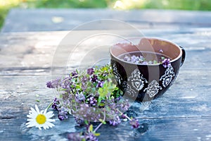 A cup of herbal tea with thyme and a bouquet of flowers