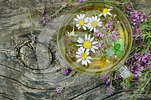 Cup of herbal tea on a wooden table top view. thyme, mint and chamomile tea. alternative medicine. cold and flu remedy