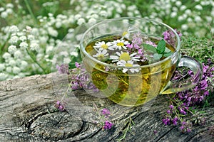 Cup of herbal tea on a wooden table top view. thyme, mint and chamomile tea. alternative medicine. cold and flu remedy