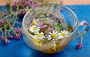 Cup of herbal tea on a wooden table top view. thyme, mint and chamomile tea. alternative medicine. cold and flu remedy