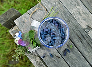 Cup with honeyberry and wildflowers on planks