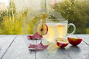 Cup of hot Apple punch in rainy autumn weather. Drink on the wooden table by the window