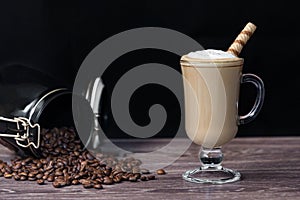 A Cup of hot aromatic coffee or cappuccino with a waffle tube on a wooden table.