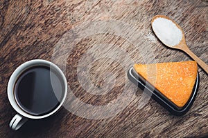 Cup of hot black coffee and cake powdered sugar on wooden tabl