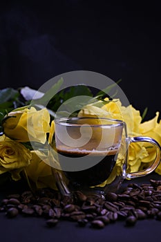 Cup of hot black coffee on coffee beans with yellow roses