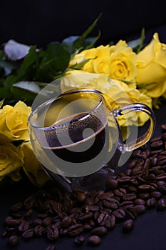 Cup of hot black coffee on coffee beans with yellow roses