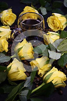 Cup of hot black coffee on coffee beans with yellow roses