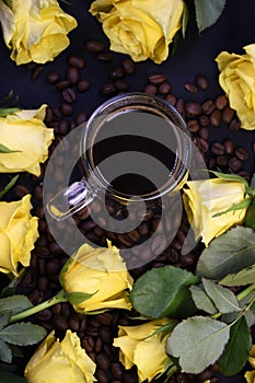 Cup of hot black coffee on coffee beans with yellow roses