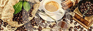 Cup of hot black coffee with old wooden mill grinder and burlap photo