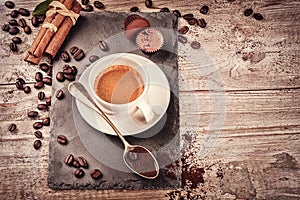 Cup of hot black coffee in setting with roasted coffee beans