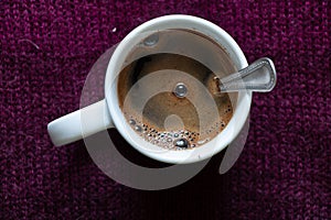 Cup of hot black coffee with a spoon on the table top to bottom view