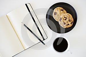 Cup of hot black coffee on white table background with notebook and stationery.  Work from home concept