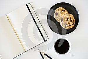 Cup of hot black coffee on white table background with notebook and stationery.  Work from home concept