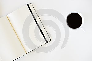 Cup of hot black coffee on white table background with notebook and stationery.  Work from home concept