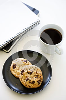 Cup of hot black coffee on white table background with notebook and stationery.  Work from home concept