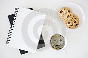 Cup of hot black coffee on white table background with notebook and stationery.  Work from home concept