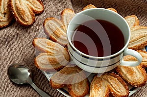 A cup of hot black tea with puff pastry.