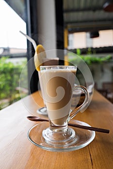 A cup of hot cappuccino with Chocolate banana smoothie and bread