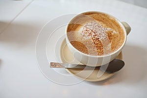 Cup of hot cappuccino coffee on table