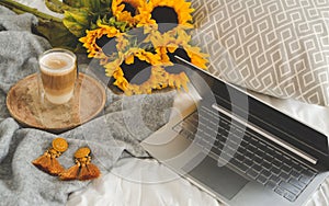 Cup with hot cappuccino, gray pastel woolen blanket, sunflowers, bedroom