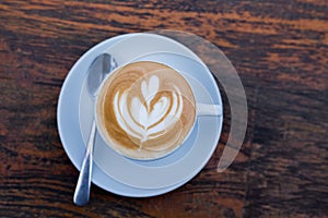 Cup of hot cappucino on wooden table background.