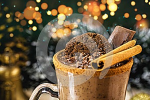 Cup of hot chocolate with a Christmas theme, a typical drink for the holidays. Spot focus on cinnamon, background with christmas
