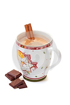 Cup of hot chocolate with cinnamon stick and pieces on white