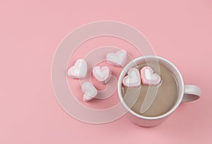 A cup of hot chocolate with  heart shape marshmallows on pink background with copy space. Valentine`s day and beverage concept