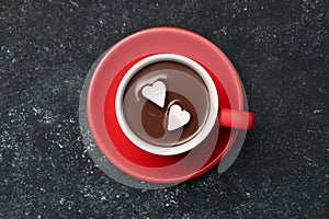 Cup of hot chocolate with heart shaped marshmallows on grey table, top view