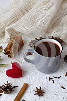 Cup of hot chocolate with marshmallows and cinnamon, anise star and knitted red heart on white background.