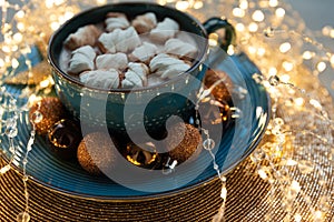 Cup of hot chocolate with marshmallows decorated Christmas baubles and defocused lights on gray wooden background. Christmas and