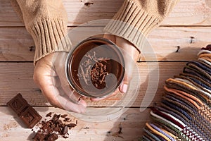 Cup of hot chocolate in woman`s hands and pieces of chocolat on wooden rustic table