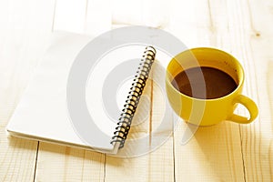Cup of hot chocolate on wooden background with notebook.  Work from home concept