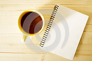 Cup of hot chocolate on wooden background with notebook.  Work from home concept