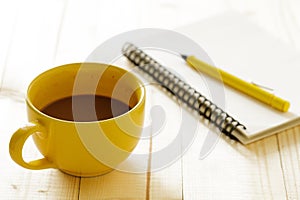 Cup of hot chocolate on wooden background with notebook.  Work from home concept