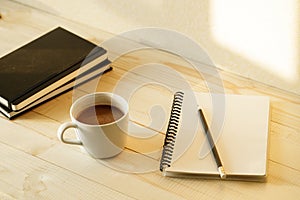 Cup of hot chocolate on wooden background with notebook.  Work from home concept