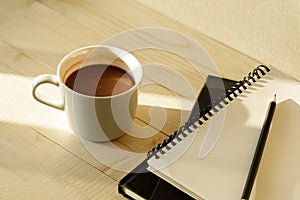 Cup of hot chocolate on wooden background with notebook.  Work from home concept
