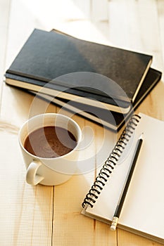 Cup of hot chocolate on wooden background with notebook.  Work from home concept