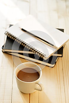 Cup of hot chocolate on wooden background with notebook.  Work from home concept