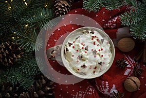 Cup of hot christmas drink with cream, walnuts and knitted pullover. Xmas still life.