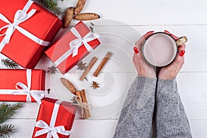 Cup of hot cocoa or chocolate in girl hands with red manicure. Flat lay, top view. Young woman in sweater with cacao mug.