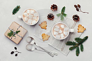 Cup of hot cocoa or chocolate with marshmallow, cookies and christmas gift on white table from above. Traditional winter drink.