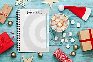 Cup of hot cocoa or chocolate with marshmallow, holiday decorations and notebook with wish list, christmas planning.