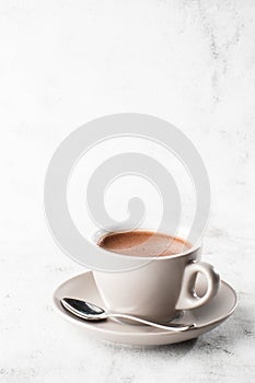 Cup of hot cocoa or hot chocolate or americano in white cup isolated on bright marble background. Overhead view, copy space.